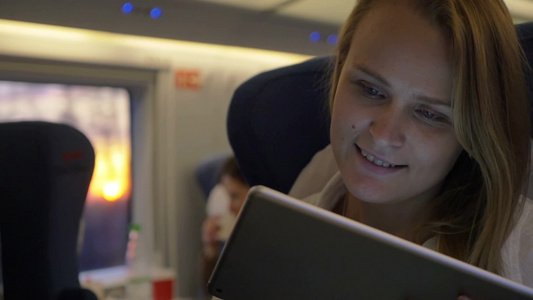 一个快乐的年轻女人在乘坐火车时使用平板电脑进行交流视频