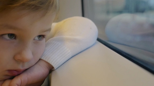 一个小男孩在火车上靠在窗台上看着窗外视频