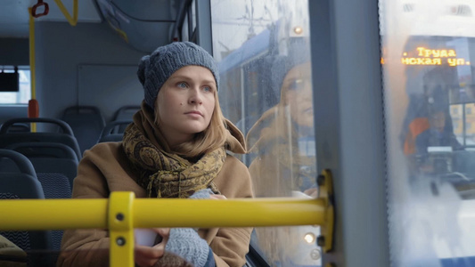 冬天一个年轻女人拿起手机看着公共汽车窗外视频