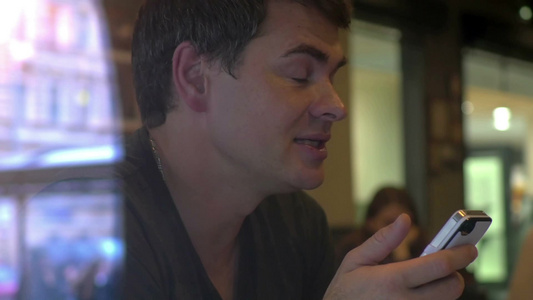 年轻人在咖啡馆里拿着智能手机与对面的朋友进行了生动的交谈视频