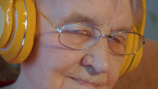 一位戴着无线耳机的老年妇女在听音乐视频