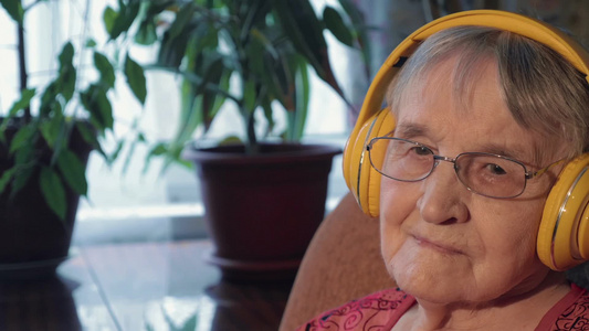 老人躺在扶手椅上戴着耳机听音乐视频