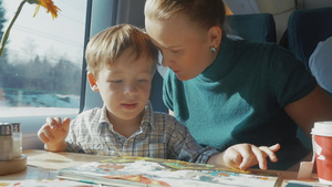 年轻的母亲和儿子在坐火车旅行时看书缓慢动作34秒视频