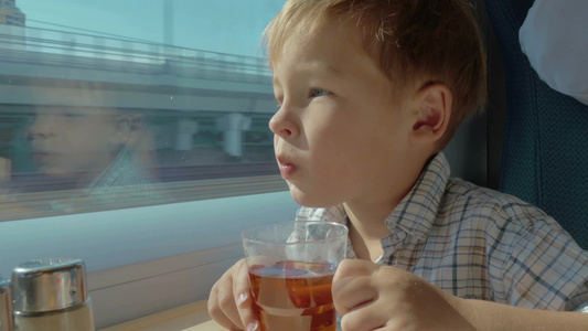 小男孩在火车上看着窗外喝茶视频