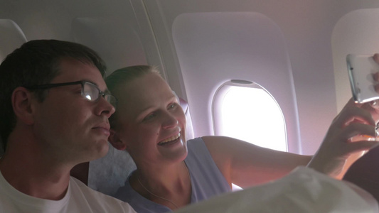 年轻夫妇使用智能手机在飞机上自拍视频