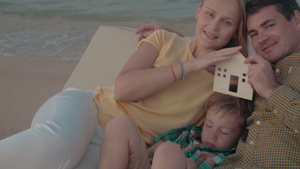年轻的家庭在海边休息拿着一座房子的模型10秒视频