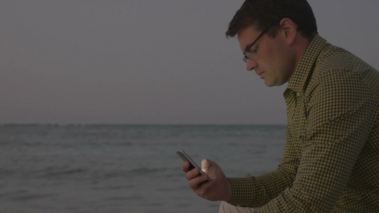 男人在海边看手机视频