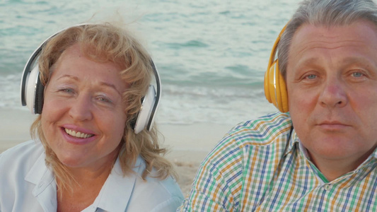 老年夫妇坐在海边耳机听音乐[老大娘]视频