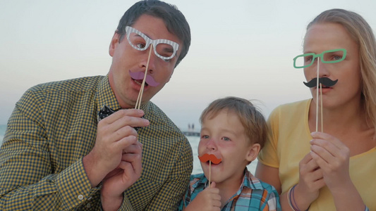 年轻的父母和小儿子戴着纸质的时髦眼镜和胡子视频