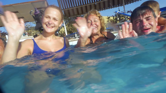 一个大家庭成员在游泳池里休息并挥动双手的慢动作镜头视频