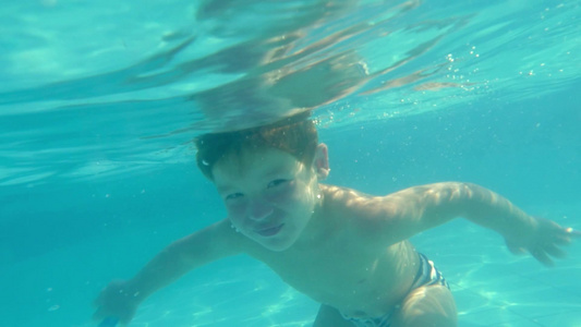小男孩在游泳池水下游泳慢动作镜头视频