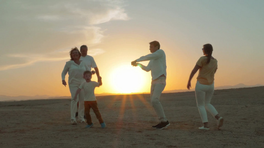 一家人在夕阳下的海滩上跳舞[一大家子]视频