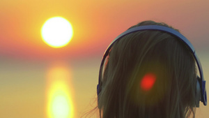 金色日落海边一个金发女人戴上无线耳机听音乐27秒视频
