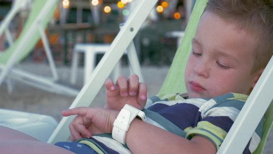 小男孩在躺椅上使用智能手表视频
