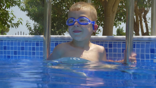 戴护目镜的小男孩在游泳池的梯子上微笑视频