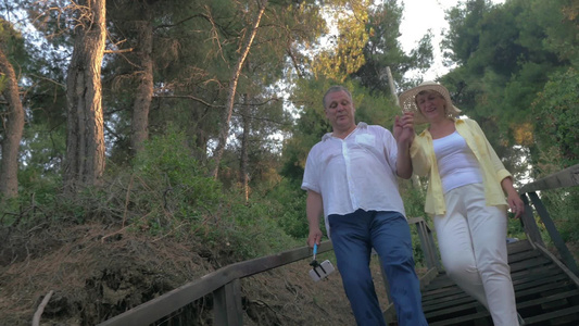 一对夫妇在森林里散步手里拿着自拍杆[遛弯儿]视频