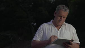 成熟的男人在黄昏时站在户外用手写笔在平板电脑上打字8秒视频