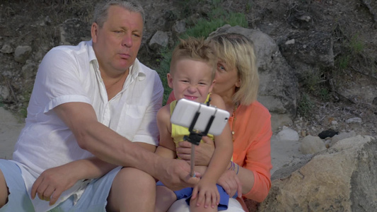 孙子和祖父母在户外做着笑脸表情用手机单脚架自拍视频