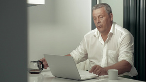 成年戴眼镜男子在厨房一边喝咖啡一边用笔记本电脑工作45秒视频
