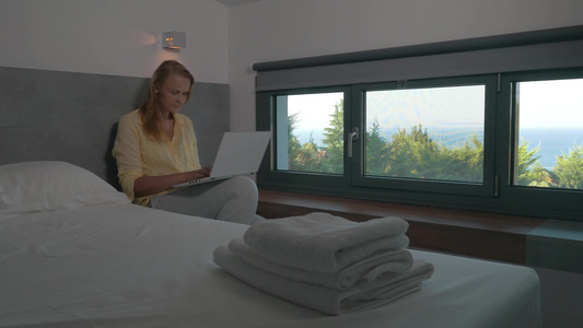 年轻女性在酒店房间窗口用笔记本电脑工作视频