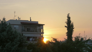 看到有阳台的房子前景是绿树和灌木丛从建筑物后面可以看到金色的日落17秒视频