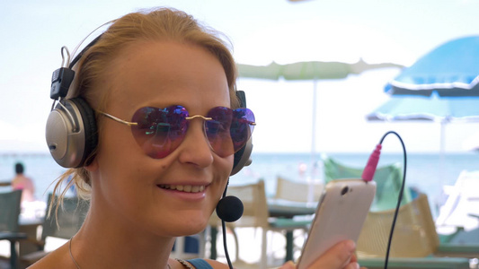 年轻女性戴着耳机使用智能手机视频聊天视频