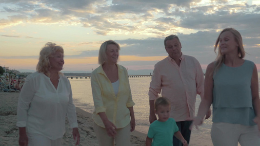 日落时在海滩上散步的一家人视频