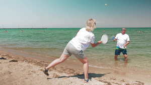 两位老人在阳光明媚的海滩上打羽毛球9秒视频