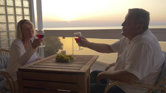 日落时在户外阳台喝红酒的夫妇[黄昏时候]视频