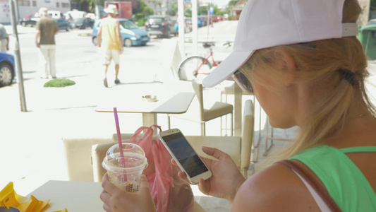 年轻女孩喝着饮料玩着手机[二十多岁]视频