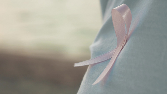 一个将象征着乳腺癌的粉红色佩戴在胸口的人物特写视频