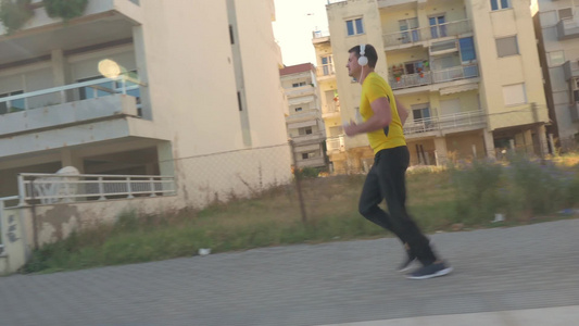戴着耳机听音乐的年轻男人在马路人行道上跑步视频