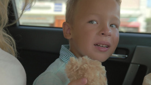 坐在车后座手里拿着毛绒玩具泰迪熊的小男孩22秒视频