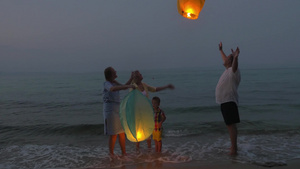 幸福的家庭在晚上站在海边释放天空灯笼13秒视频