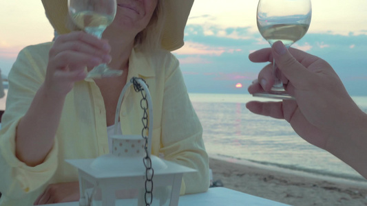 夕阳下一对老年夫妇坐在海边的餐厅里一起喝着葡萄酒享受着幸福时光视频