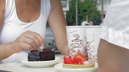 一对男女坐在街头的咖啡馆喝着咖啡品尝草莓甜点视频