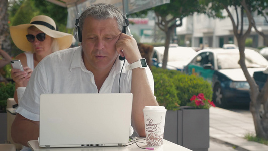 老人戴着耳机在咖啡馆里用笔记本电脑进行视频聊天视频
