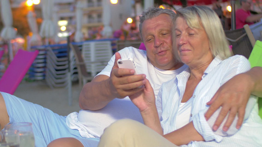 老年夫妇在海滩上玩智能手机视频