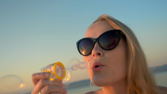 一个漂亮的金发女人戴着太阳镜吹泡泡视频