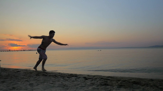 慢动作拍摄的年轻人在海滩上表演翻筋斗视频