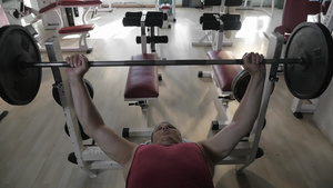 一个肌肉发达的老人在健身房里杠铃锻炼的慢动作59秒视频