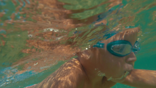 戴着护目镜潜水的小男孩在水下快乐的游泳[戴起]视频