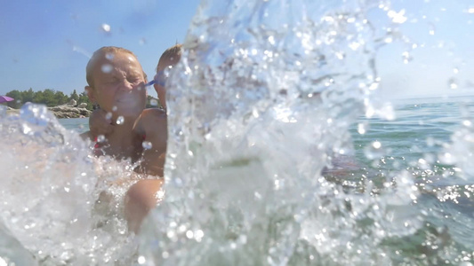 在海上母亲和父亲抱着一个顽皮的男孩向相机泼水视频