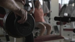 在健身中心妇女用固定重量板的杠铃锻炼特写16秒视频