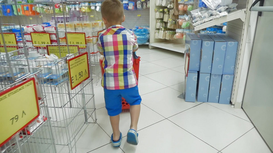 一个小男孩在超市里推着塑料购物车视频