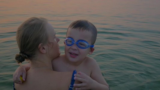 母亲抱着的儿子在海里学游泳视频