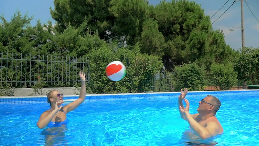 一个快乐的父亲和成年女儿在游泳池里打排球视频