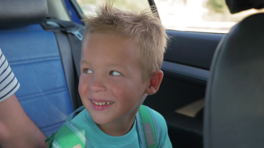 坐在汽车后座上的可爱的金发小男孩视频