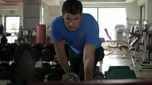 一个强壮的男人在健身房戴着耳机听音乐同时锻炼哑铃44秒视频