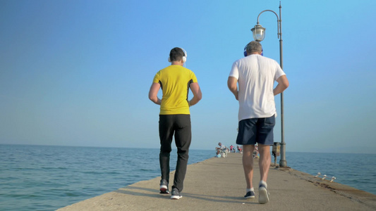 在海边倒着跑步的两个男人视频